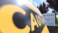 A caution sign sits on a sidewalk in front of the Gilead Sciences headquarters in Foster City, California on April 30, 2020. Gilead Science's remdesivir, one of the most highly anticipated drugs being tested against the new coronavirus, showed positive re