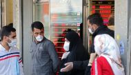 Iranians, wearing protective masks without observing social distancing, queue outside a money exchange office in the capital Tehran on May 9, 2020, during the coronavirus (COVID-19) pandemic.   AFP / ATTA KENARE