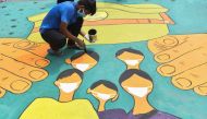 An artist paints a floor mural dedicated to police forces to thank their service braving all risks during a nationwide lockdown to fight the spread of the COVID-19 coronavirus, in Mumbai on May 16, 2020. / AFP / INDRANIL MUKHERJEE
