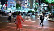 A woman wearing a face mask crosses a street in Tokyo’s Shinjuku area on May 25, 2020. (AFP / CHARLY TRIBALLEAU)