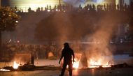 A member of the Lebanese security forces walks toward rubbish containers set ablaze by anti-government protesters, during a demonstration against dire economic conditions, under the Fuad Shehab bridge known as the Ring, in the capital Beirut, late on June
