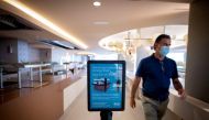 An employee wearing a face mask walks past a sign with security measures at the RIU Concordia Hotel in Palma de Mallorca on June 10, 2020 as the Balearic Islands prepare to welcome German tourists from June 15 as a test before Madrid reopens international