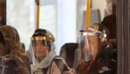 Passengers, wearing face shields due to the COVID-19 coronavirus, sit inside a bus in the Iranian capital Tehran on June 22, 2020. / AFP / ATTA KENARE