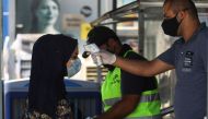 A costumer, wearing a protective mask due to the COVID-19 pandemic, has her temperature checked before entering a supermarket in the Iraqi capital Baghdad, on June 23, 2020. / AFP / AHMAD AL-RUBAYE