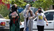 Pedestrians, wearing protective masks due to the COVID-19 coronavirus, walk past shops in the Iranian capital Tehran on June 28, 2020.  / AFP / ATTA KENARE