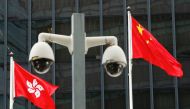 FILE PHOTO: Hong Kong and Chinese national flags are flown behind a pair of surveillance cameras outside the Central Government Offices in Hong Kong, China July 20, 2020. REUTERS/Tyrone Siu/File Photo