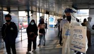 A worker wearing protective suit holds a placard with total positive cases of the coronavirus disease (COVID-19) written on it, at a central bus spot in Jakarta, Indonesia, July 27, 2020. REUTERS/Willy Kurniawan