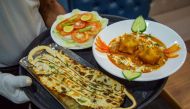 A waiter carries 'Covid Curry' and 'Mask Naan,' two Covid-19 coronavirus-themed dishes, to serve to customers at their restaurant in Jodhpur on August 3, 2020. / AFP / SUNIL VERMA