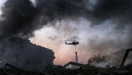  A helicopter puts out a fire at the scene of an explosion at the port of Lebanon's capital Beirut on August 4, 2020. / AFP / STR