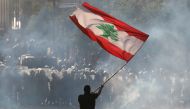 A demonstrator waves the Lebanese flag in front of riot police during a protest in Beirut, Lebanon, August 8, 2020. (Reuters/Goran Tomasevic)