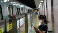 A woman wearing a face mask following the coronavirus disease (COVID-19) outbreak looks at her smartphone while waiting for a subway in Beijing, China August 11, 2020. REUTERS/Tingshu Wang