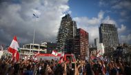 A crowd cheers members of the Lebanese Civil Defence during a commemoration ceremony for the victims of the Beirut port explosion across from the capital's harbour, on August 11, 2020. / AFP / PATRICK BAZ
