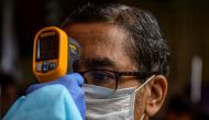 A health worker checks the body temperature of a resident during a COVID-19 coronavirus screening in Mumbai on August 12, 2020. / AFP / INDRANIL MUKHERJEE