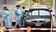 Medical staff prepare to take a swab at a drive-through testing clinic in Melbourne on August 13, 2020. Australia's virus-hit Victoria state reported a major drop in new coronavirus cases on August 13, but officials warned against complacency amid a 
