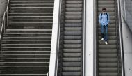 A man wearing a protective mask rides an escalator at the financial and business district of La Defense as France reinforces mask-wearing in public places as part of efforts to curb a resurgence of the coronavirus disease (COVID-19) across the country, ne