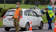 Police and military personnel check vehicles leaving the city at a COVID-19 check point setup at the southern boundary in Auckland on August 14, 2020. New Zealand rushed to track the source of a sudden return of the coronavirus as the number of new cases 