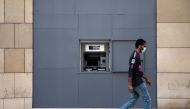 A man wearing a face mask walks past a fortified Blom Bank ATM machine, as Lebanon imposed a partial lockdown for two weeks starting on Friday in an effort to counter the spread of the coronavirus disease (COVID-19), in Beirut, Lebanon August 21, 2020. RE