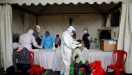 FILE PHOTO: A healthcare worker wearing personal protective equipment (PPE) takes a swab from a migrant worker, who returned to Delhi from his native state, for a rapid antigen test at a bus terminal, amidst the coronavirus disease (COVID-19) outbreak in 