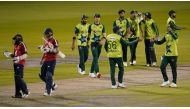 England's Tom Curran and England's Adil Rashid leave the field as Pakistan players celebrate winning by five runs after the international Twenty20 Cricket match between England and Pakistan at Old Trafford Cricket ground in Manchester, north-west England,