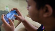 This picture taken on August 22, 2020 shows stateless eSports player Muhammad Aiman Hafizi Ahmad, 20, playing PlayerUnknown's Battlegrounds (PUBG), an online multiplayer gaming on his mobile phone at a house used by his gaming team in Bangi town, south of