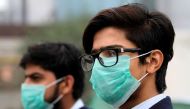 FILE PHOTO: Men wearing protective masks wait for a bus in Lahore, Pakistan November 22, 2019. REUTERS/Mohsin Raza
