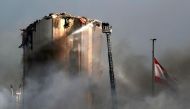 Lebanese firefighters stand on a ladder amid billowing smoke as they extinguish the remaining flames at the seaport of Beirut, on September 11, 2020, a day after a huge fire erupted in harbour warehouses. / AFP / ANWAR AMRO
