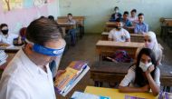 Syrian pupils, some wearing protective face masks, take their seats in class in the capital Damascus on September 13, 2020, during the first day of the school year. / AFP / LOUAI BESHARA