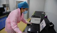 This photo taken on September 27, 2020 shows a technician in Beijing checking test results using the Flash 20 (at rear), a machine developed by Chinese biotech company Coyote as a fast test for the COVID-19 coronavirus. / AFP / GREG BAKER
