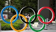 A woman wearing a protective mask amid the coronavirus disease (COVID-19) outbreak, takes a picture of the Olympic rings in front of the National Stadium in Tokyo, Japan October 14, 2020. REUTERS/Kim Kyung-Hoon