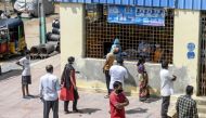 Residents wait as a health worker (C background) collects a swab sample from a man to test for the Covid-19 coronavirus before going to a medical camp for flood victims at a slum area following heavy rains in Hyderabad on October 16, 2020. AFP / NOAH SEEL