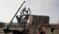 Lebanese activists erect a metalic monument on October 16, 2020, with 'October 17' written on it in Arabic, a day ahead of the one year anniversary of the beginning of a nationwide anti-government protest movement, in front of the devastated port of the c