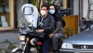 Iranians wear face masks as a COVID-19 coronavirus pandemic precaution, in Iran's capital Tehran on October 14, 2020. / AFP / ATTA KENARE