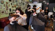 Men have their haircut at a barber shop in Melbourne on October 19, 2020, as some of the city's three-month-old stay-at-home restrictions due to the COVID-19 coronavirus outbreak were further eased on falling infection rates. AFP / William West 