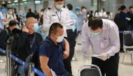 This handout photo taken on October 20, 2020 and released on October 21 by the Airports of Thailand company shows members of a group of 39 Chinese visitors with special tourist visas going through arrival measures to halt the spread of the COVID-19 corona