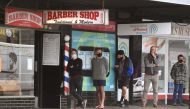Men queue for a haircut outside a barber shop in Melbourne on October 19, 2020, as some of the city's three-month-old stay-at-home restrictions due to the COVID-19 coronavirus outbreak were further eased on falling infection rates. / AFP / William WEST