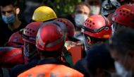 Search and rescue teams carry Sefer Perincek, mother of three, on a stretcher after pulling her out of the rubble of a collapsed building on October 31, 2020, in Izmir. AFP / OZAN KOSE