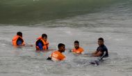 Sri Lankan Navy soldiers try to push back a stranded pilot whale into the deep water in Panadura on November 3, 2020. AFP / Lakruwan WANNIARACHCHI