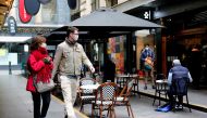 FILE PHOTO: People walk past a cafe after the coronavirus disease (COVID-19) restrictions were eased for the state of Victoria, in Melbourne, Australia, October 28, 2020. REUTERS/Sandra Sanders/File Photo
