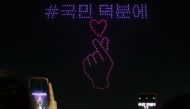 Spectators take photos as 315 illuminated drones perform a routine to display messages and images of support for South Korea amid the COVID-19 coronavirus pandemic, at a park in Seoul on November 13, 2020. - South Korea OUT