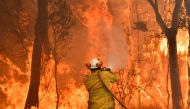 This file photo taken on December 10, 2019 shows a firefighter conducting back-burning measures to secure residential areas from encroaching bushfires in the Central Coast, some 90-110 kilometres north of Sydney. / AFP / Saeed KHAN