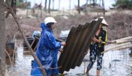 Residents carry part of a damaged roof following high winds and rain brought by Typhoon Vamco as it made landfall in Thua Thien Hue province on November 15, 2020. / AFP / Huy THANH