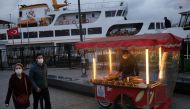 People wearing protective masks walk past by a street vendor selling roasted chestnuts, amid the spread of coronavirus disease (COVID-19), in Istanbul, Turkey November 10, 2020. REUTERS/Murad Sezer
