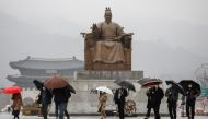 Pedestrians wearing masks walk with umbrellas as it rains amid the coronavirus disease (COVID-19) pandemic in central Seoul, South Korea, November 19, 2020. REUTERS/Heo Ran
