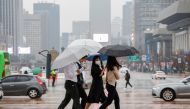 Pedestrians wearing masks walk with umbrellas as it rains amid the coronavirus disease (COVID-19) pandemic in central Seoul, South Korea, November 19, 2020. REUTERS/Heo Ran