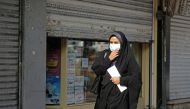 A woman wearing a face mask amid the COVID-19 pandemic walks by closed shops in the Iranian capital Tehran, on November 30, 2020. / AFP / ATTA KENARE