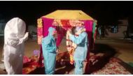 A bride and groom wearing personal protective equipment (PPE) exchange flower garlands during a wedding ritual in Baran, Rajasthan, India December 6, 2020, in this still image taken from video. ANI/Reuters 