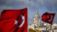 In this photo taken on December 6, 2020 the Galata tower is pictured next to Turkish national flags in Istanbul during a week-end curfew aimed at curbing the spread of the Covid-19 pandemic caused by the novel coronavirus. AFP / Ozan KOSE
