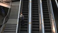 A woman wearing a face mask as a preventive measure against the Covid-19 coronavirus rides an escalator at Seoul railway station in Seoul on December 22, 2020. / AFP / Jung Yeon-je