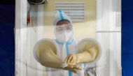 A health worker wearing a protective suit amid the coronavirus disease (COVID-19) pandemic disinfects her hands at a testing station, in Makati City, Metro Manila, Philippines, December 21, 2020. REUTERS/Lisa Marie David