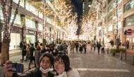 A couple takes pictures in front of Christmas-themed light decorations along a street in Marunouchi district in Tokyo on December 25, 2020. / AFP / Philip FONG